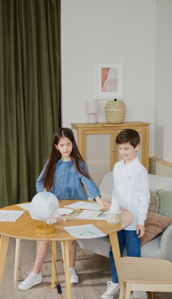 Two children interact with educational materials on a table, indicating a learning environment.